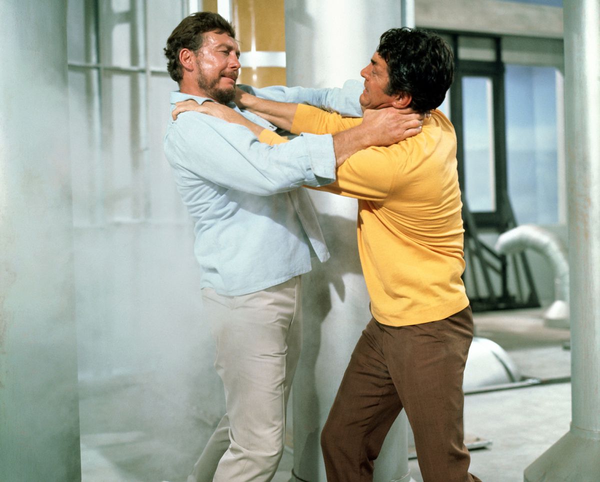 Matt Helm i en gul tröja kväver en skäggig kille i khakis på ett rymdskepp i The Ambushers