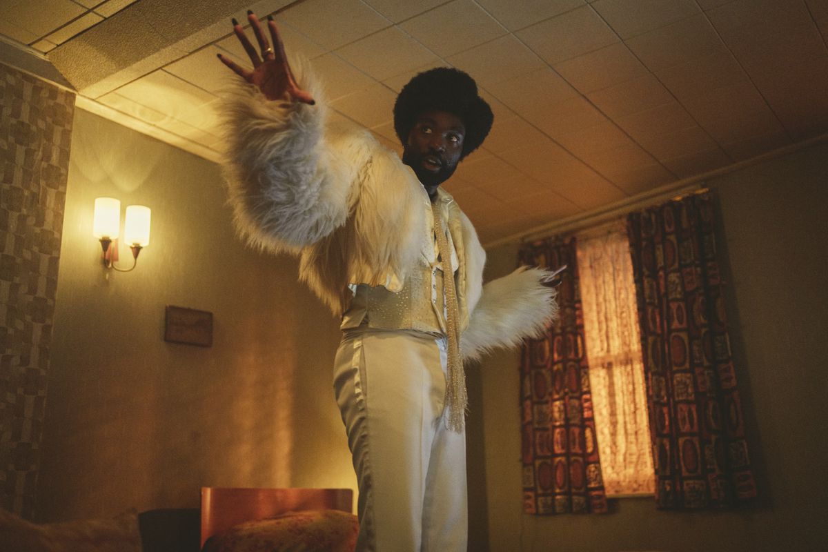 Paapa Essiedu i en flamboyant vit outfit tittar på något i en stillbild från Black Mirror säsong 6
