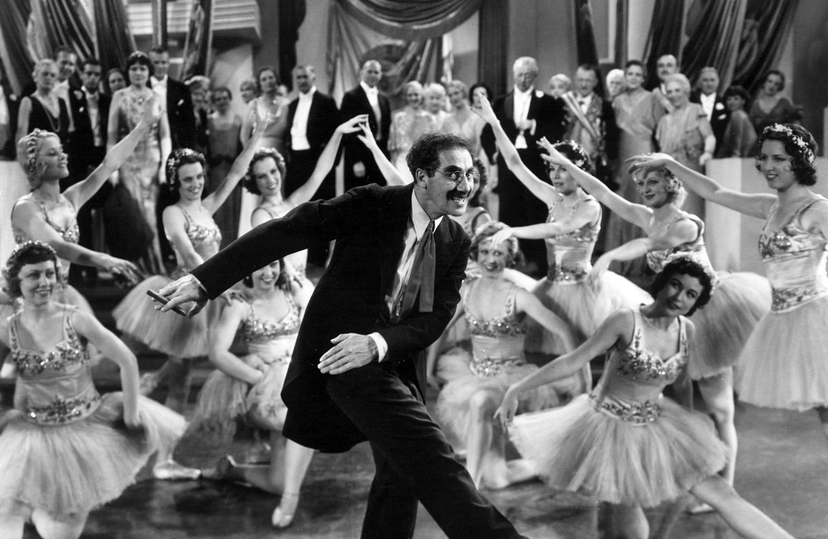 Groucho Marx dancing in front of a large crowd in Duck Soup
