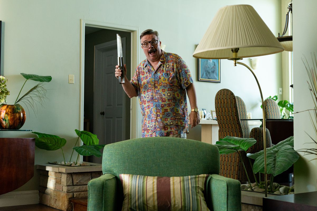 Nathan Lane bär en hawaiiansk skjorta och håller tång i Beau is Afraid.