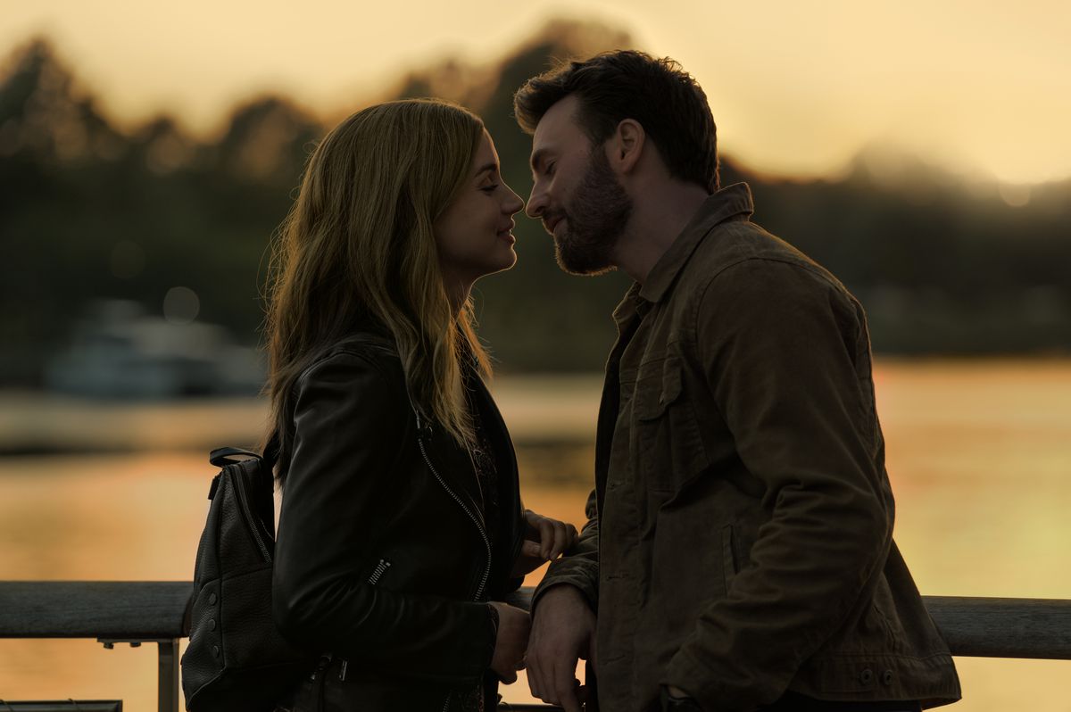 Cole (Chris Evans) och Sadie (Ana de Armas) lutar sig in för en kyss vid magiska timmen, en solnedgångssjö bakom dem i bakgrunden i Ghosted