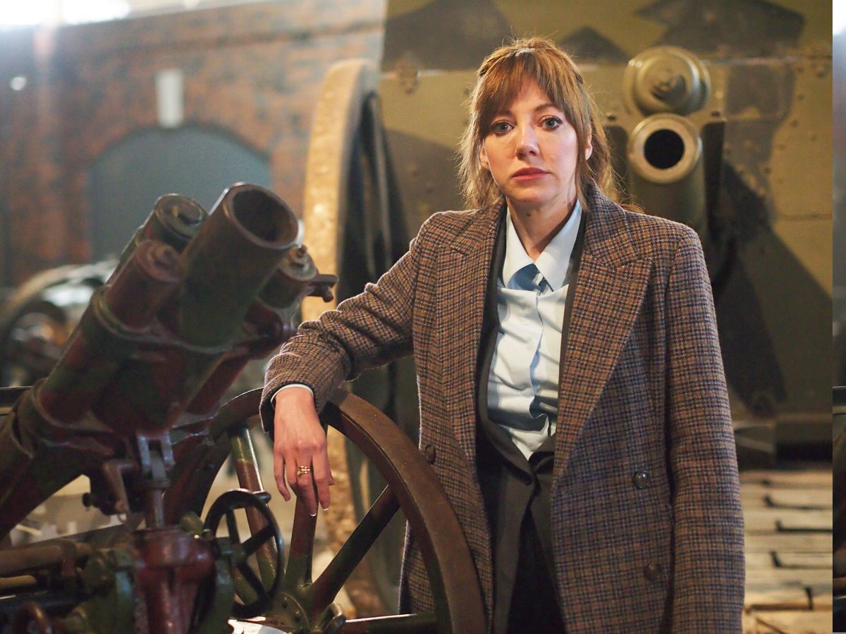 Diane Morgan as Philomena Cunk wears a brown tweed jacket and leans on a cannon.