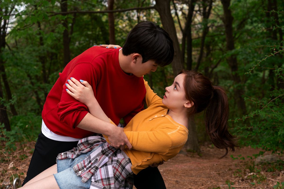 A young Korean man catches a teenage girl as she falls on a hike