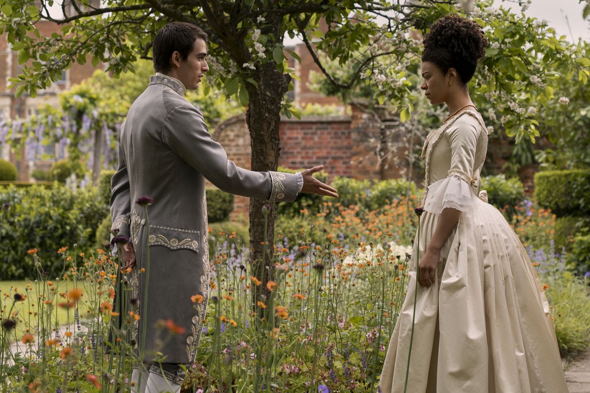 king george offers a hand to a young queen charlotte in a garden