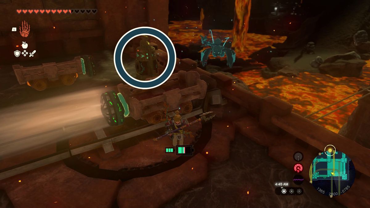 A blue circle highlights a bell-like mechanism next to the minecarts in Tears of the Kingdom’s Fire Temple