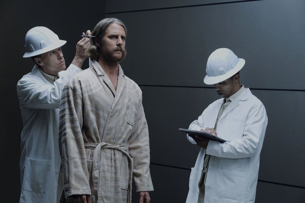 Wiley (Jake McDormand) inspekteras av två män i labbrockar och hjälm i en stillbild från Mrs Davis säsong 1