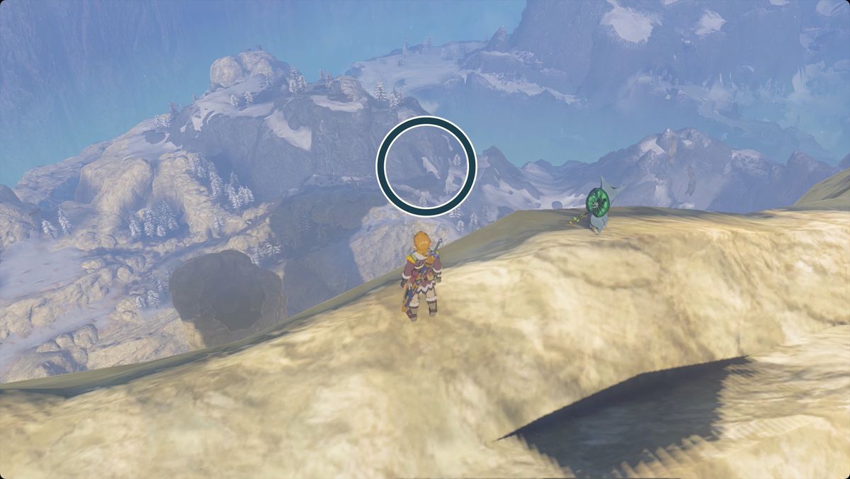 The Legend of Zelda: Tears of the Kingdom Link (och en Korok) som står på Van Medohs Abborre och ser västerut.  En fläck som nu liknar en vit fågel på ett närliggande berg är inringad