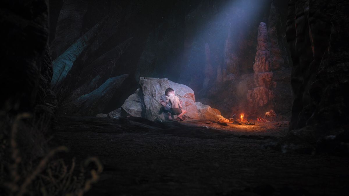 I en mörk grotta upplyst av en liten eld och en ljusstråle från himlen hukar Gollum med ryggen mot 