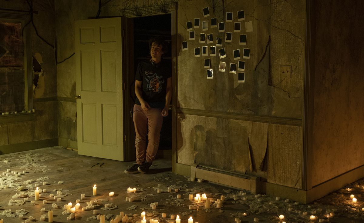 Rob Savage står i ett fallfärdigt hem med polaroider på väggen upplysta av ljus aka uppsättningen av The Boogeyman