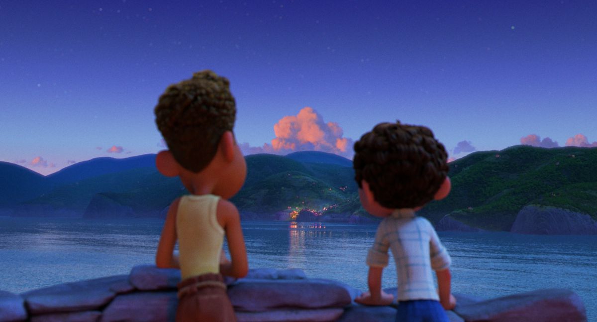 Luca och Alberto tittar ut på en stad på andra sidan vattnet på kvällen