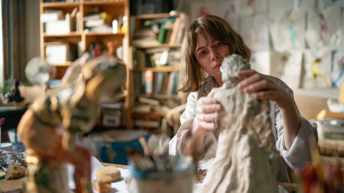 Michelle Williams molding a sculpture in an art studio in Showing Up.