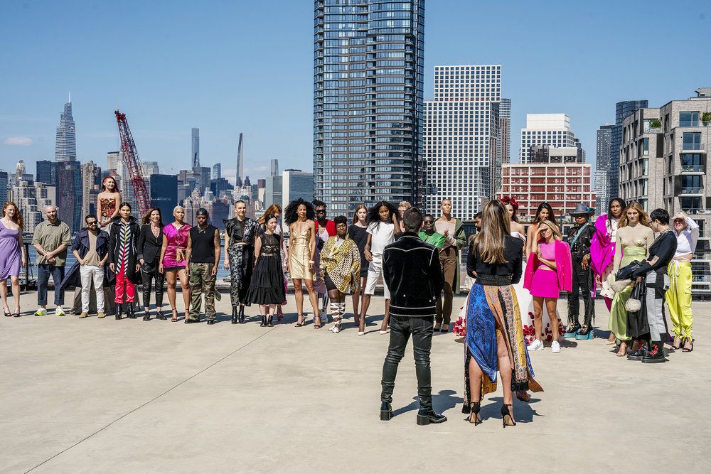 Skådespelarna i Project Runway säsong 20 står och lyssna på värdarna framför en New Yorks skyline