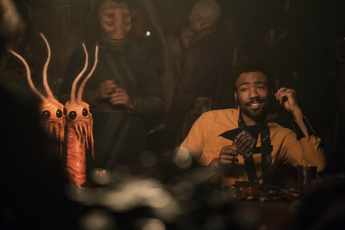 Donald Glover som Lando Calrissian i Solo: A Star Wars story.  Han sitter smarrigt vid ett sabacc-spelbord, omgiven av konstiga utomjordingar. 