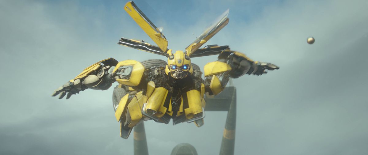 Bumblebee, a yellow Transformer with glowing blue eyes, flies into battle with all his panels unfolded so he just looks like a spiky metal ball with a face in Transformers: Rise of the Beasts