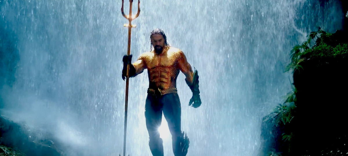 Aquaman - Aquaman håller en treudd som står framför ett vattenfall