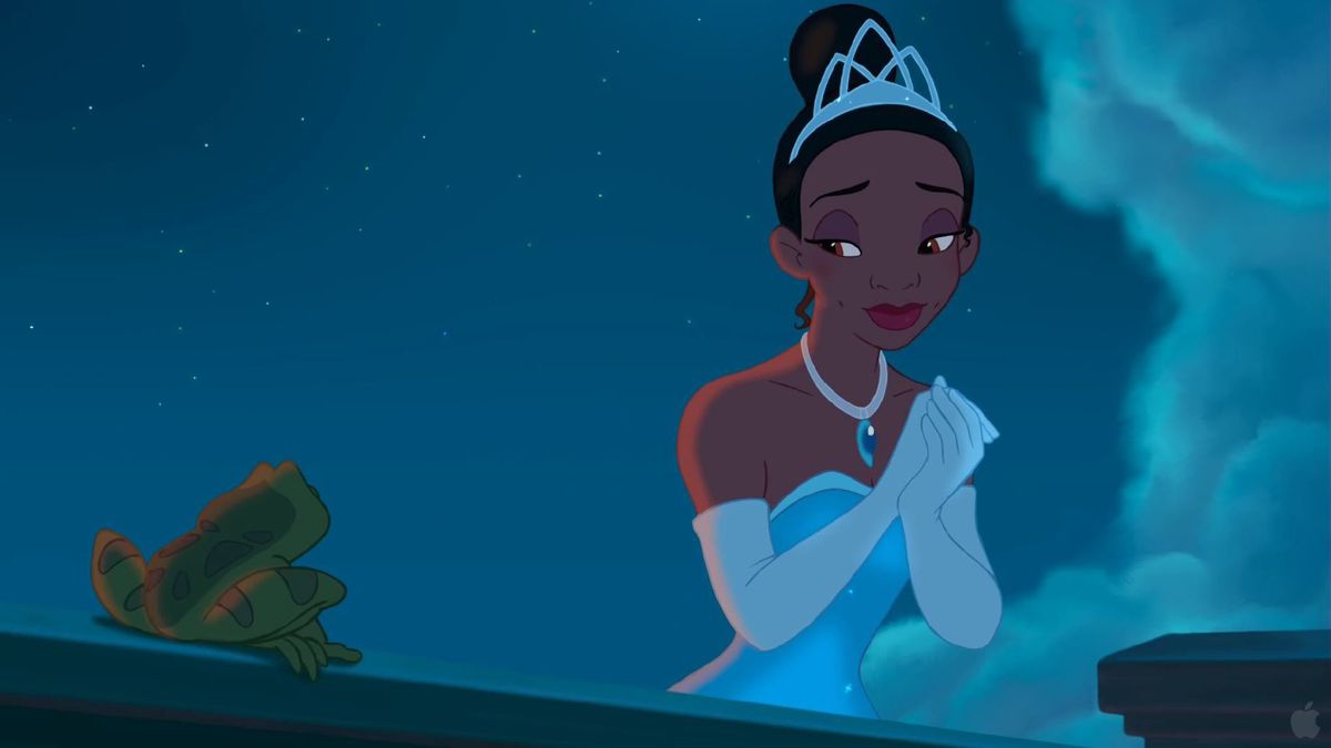 Tiana, en svart kvinna i tiara, silverrock och vita operahandskar, slår ihop händerna och ler mot en groda bredvid henne i Disneys The Princess and the Frog