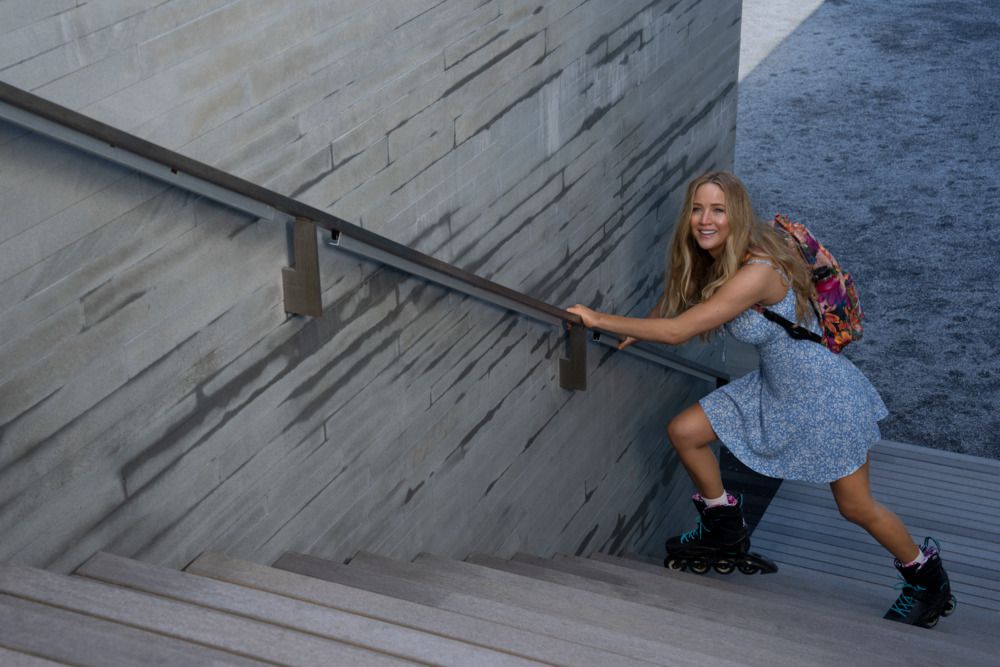 Jennifer Lawrence försöker klättra uppför en trappa i rullblad samtidigt som hon håller i räcket i filmen No Hard Feelings.