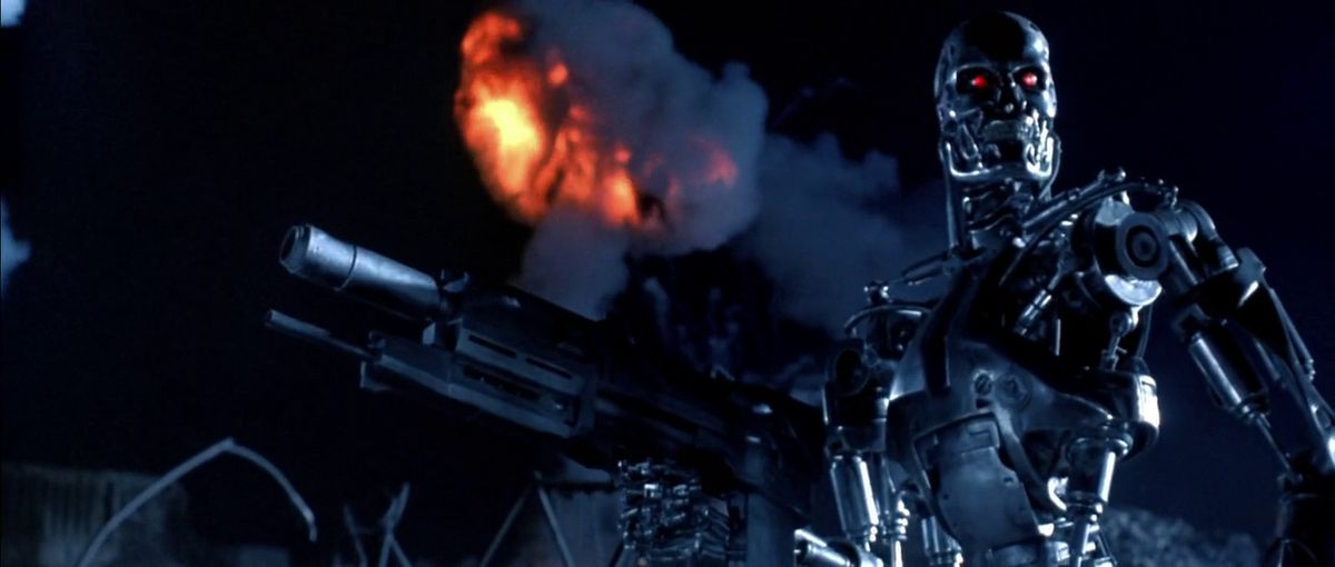 Ett exoskelett av T-800 Terminator som kartlägger ett slagfält med ett stridsgevär i handen när en brinnande rökplym sticker ut i fjärran i Terminator 2: Judgment Day.