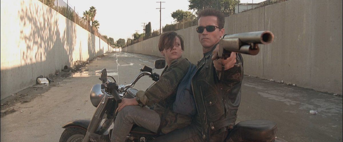 (LR) Edward Furlong och Arnold Schwarzenegger som John Conner och en omprogrammerad T-800 Terminator som håller ett hagelgevär på toppen av en motorcykel på tomgång i en ravin i Terminator 2: Judgment Day. 