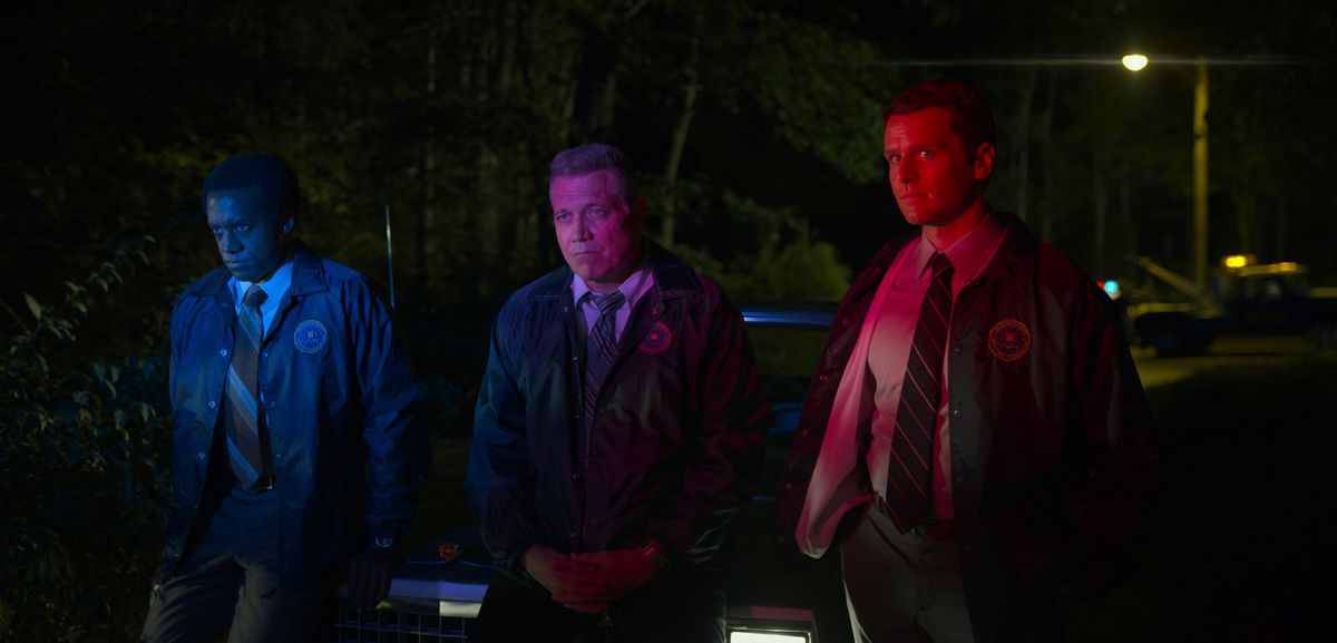 Albert Jones, Holt McCallany, Jonathan Groff lutad mot huven på en bil medan de tänds av polissirenerna i avsnitt fem av Mindhunter säsong 2.