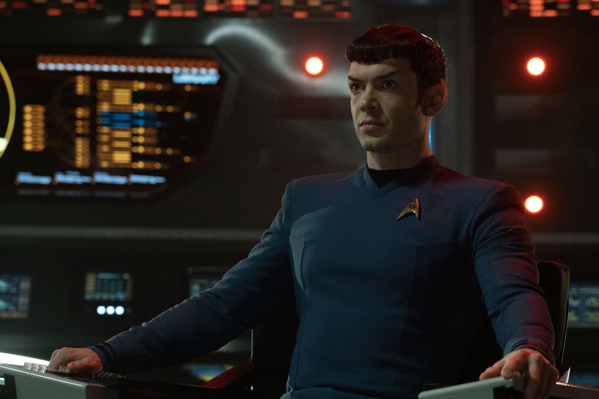 Ethan Peck som Spock, sittande i kaptensstolen på en förmörkad bro i Strange New Worlds. 