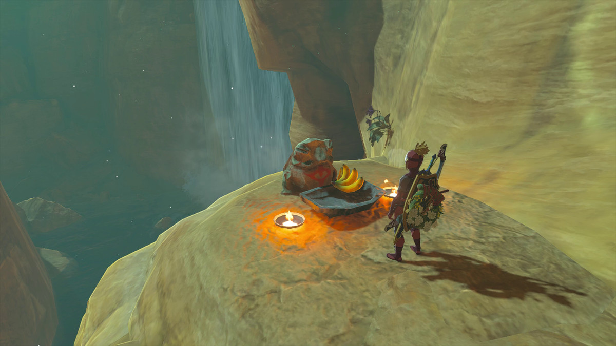 Link står framför en groda med en Yiga Clan-symbol på i Tears of the Kingdom.  Det finns två facklor vid grodan med en banan som erbjuds framför.