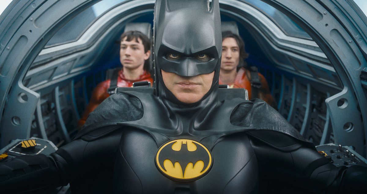 (LR) Ezra Miller som The Flash, Michael Keaton som Batman och Ezra Miller som The Flash in The Flash.  De är i den trånga cockpiten på Batwing, med Batman i pilotsätet och de två blixtarna som sitter bredvid varandra bakom honom.