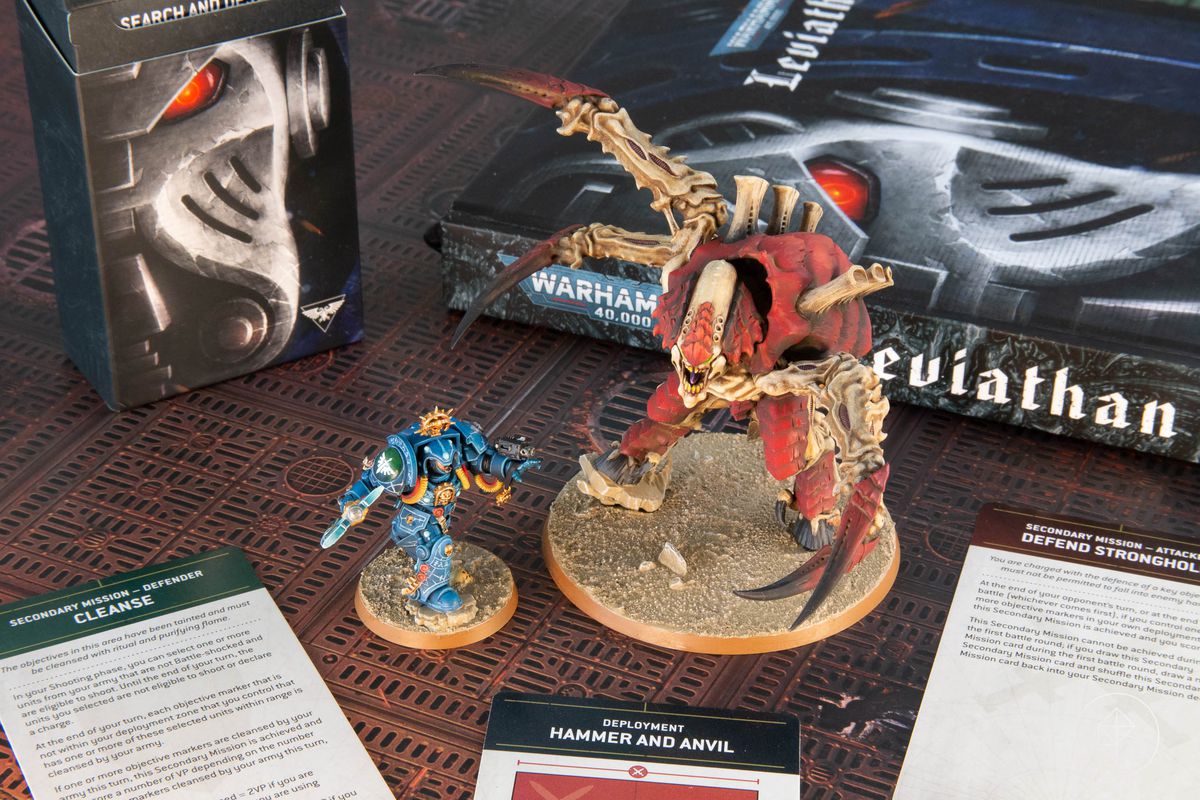Två pro-målade miniatyrer från Warhammer 40 000: Leviathan, en inbunden regelbok och ett urval av uppdragskort.