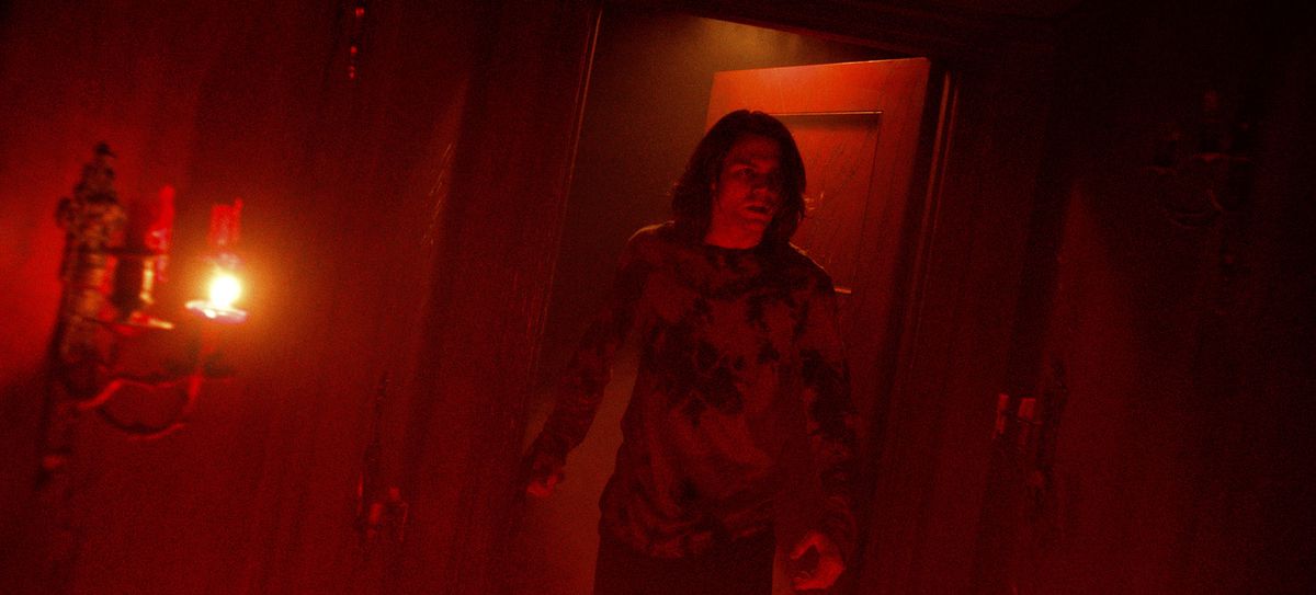 Dalton (Ty Simpkins), a tall, gangly, shaggy-haired teenager, enters a room lit entirely in dark red light in Insidious: The Red Door