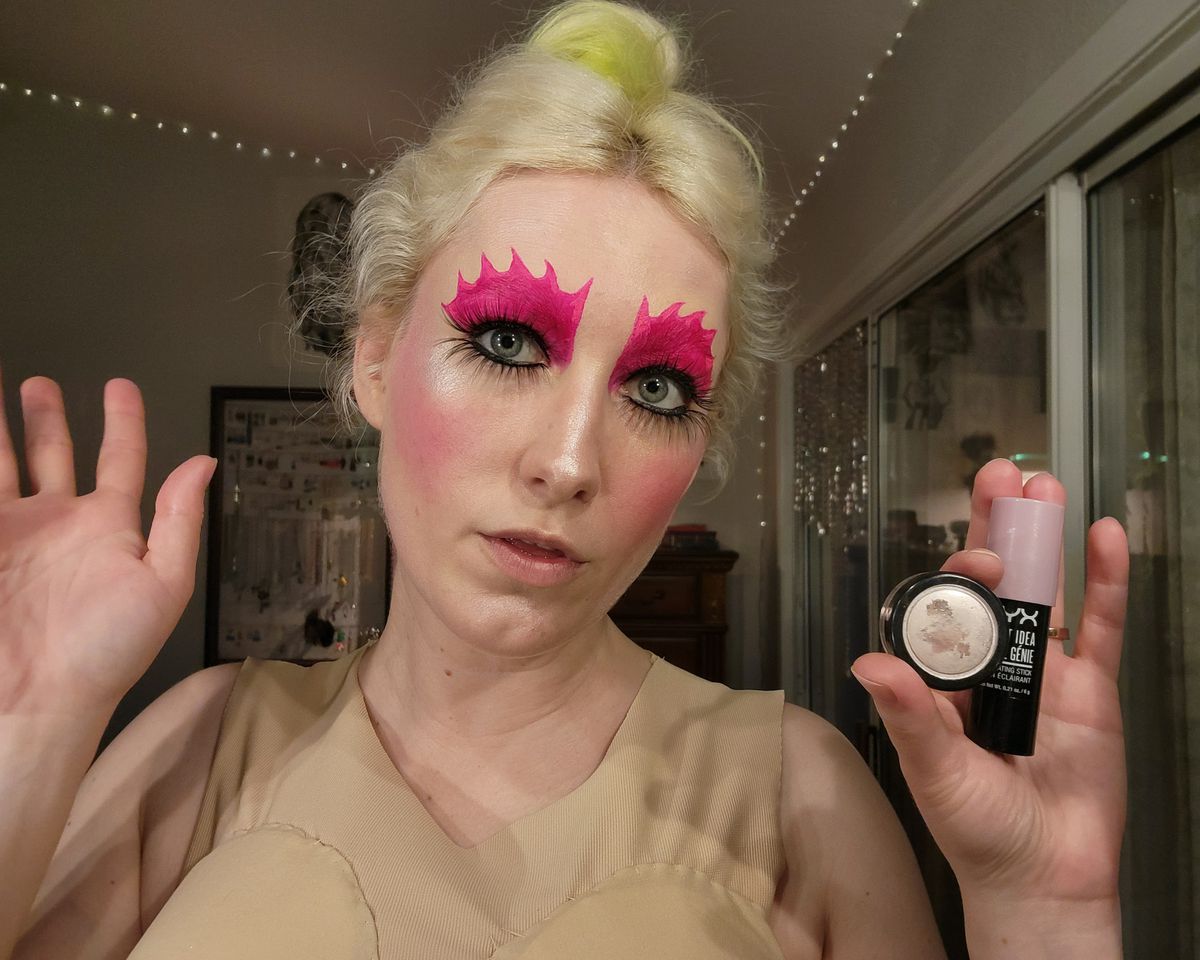 The author with highlighter on, holding the products she used to create her look