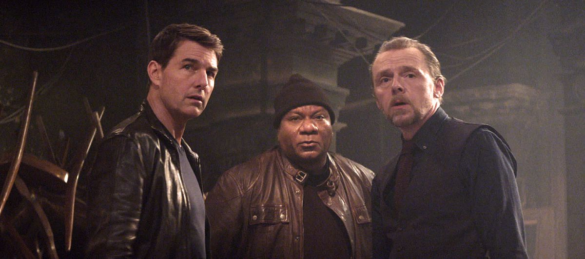 Ethan Hunt (Tom Cruise), Luther Stickell (Ving Rhames, i en svart mössa och läderjacka) och Simon Pegg (i en svart-på-svart kostym) står i en halvcirkel i Mission: Impossible Dead Reckoning Part One