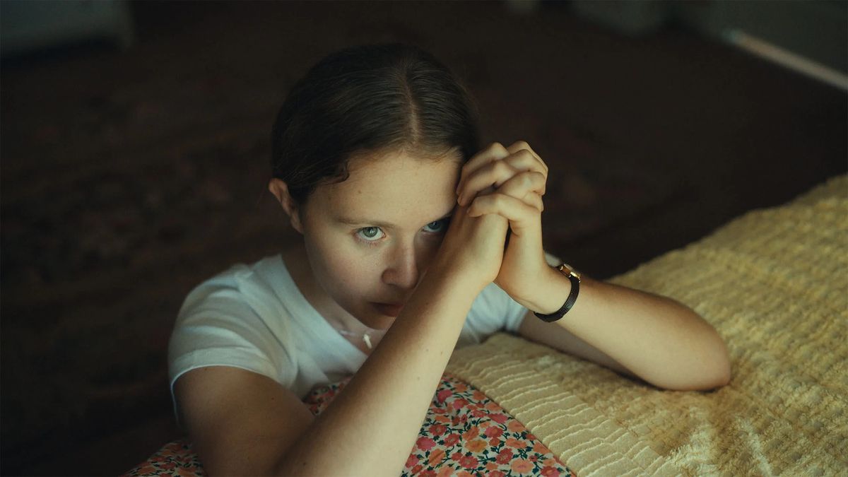 Eliza Scanlen som Jem Starling knäböjer framför en säng och ber i The Starling Girl.