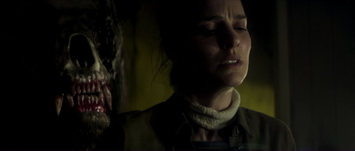 Natalie Portman som Lena, en biolog som är bunden till en stol medan hon håller andan medan en hotfull mutant björnvarelse slår sina tänder över hennes axel i Annihilation.