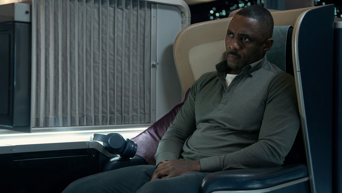 Idris Elba sittande i ett flygplanspassagerarsäte och såg strängt ut i kapning.