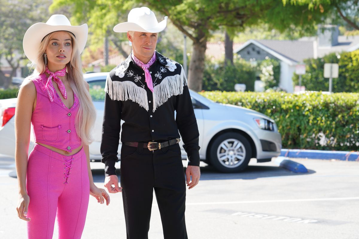 Margot Robbie som Barbie, klädd i en rosa cowgirl-outfit, står bredvid Ken, som bär en matchande svart cowboypassform. 