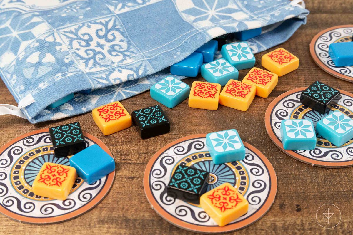 En påse med mångfärgade brickor som rinner ur den från brädspelet Azul
