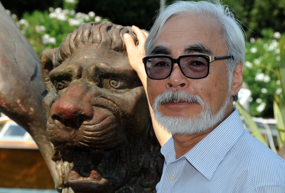 Den japanske regissören Hayao Miyazaki står bredvid en staty av ett stiliserat lejon med en hand på huvudet i Venedig, Italien 2008.