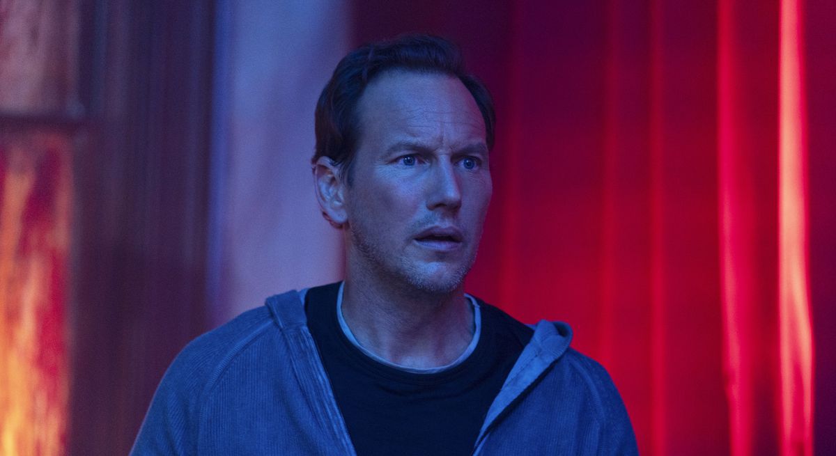 Josh (Patrick Wilson) stands in a neon-lit, mostly red room and looks shocked at something offscreen in Insidious: The Red Door