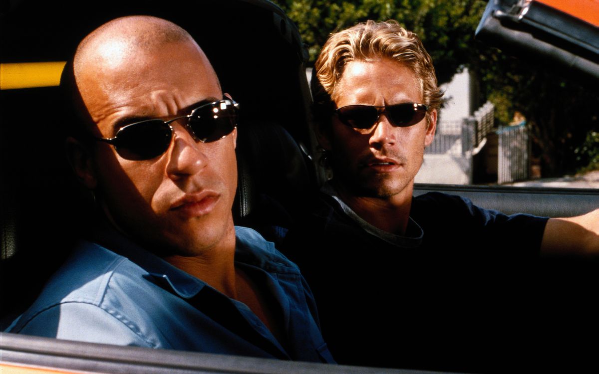 Vin Diesel och Paul Walker bär solglasögon med fårade bryn i en cabriolet i The Fast and The Furious