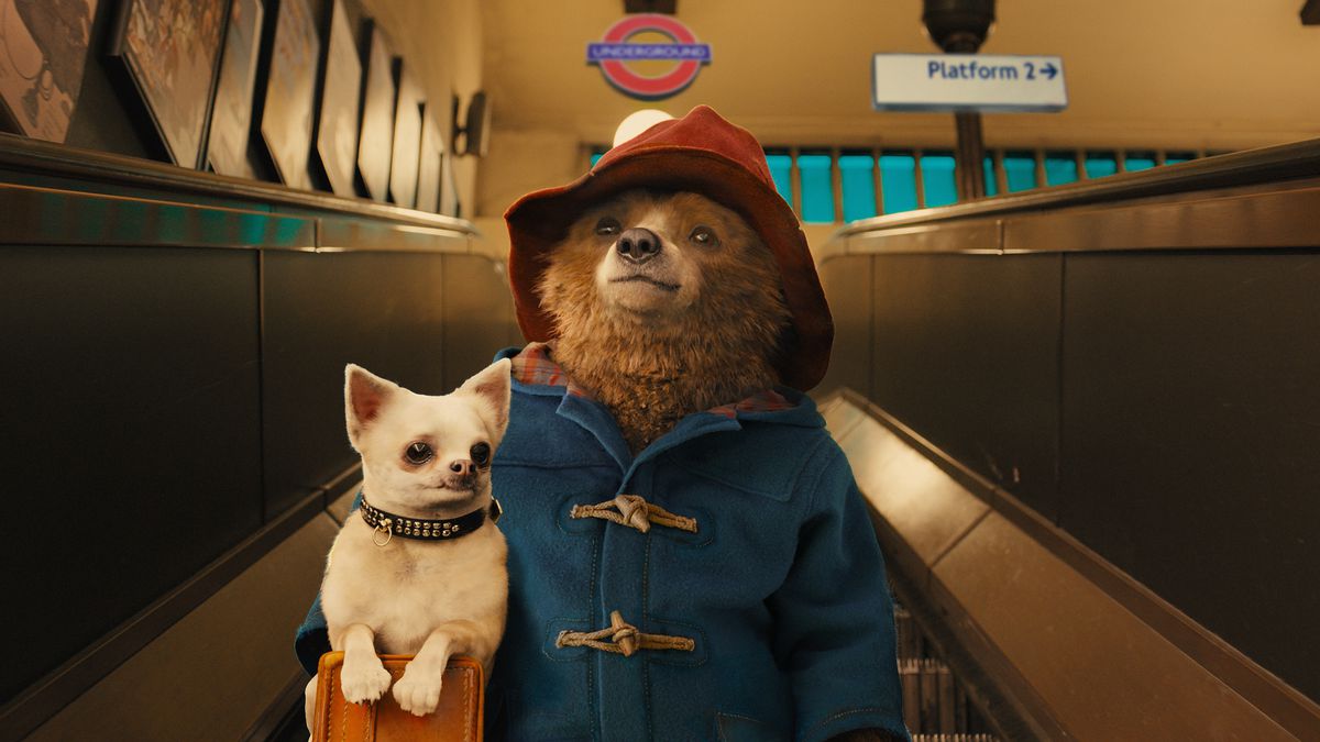 Ben Whishaw as Paddington holding a puppy while descending a subway escalator in Paddington (2014).