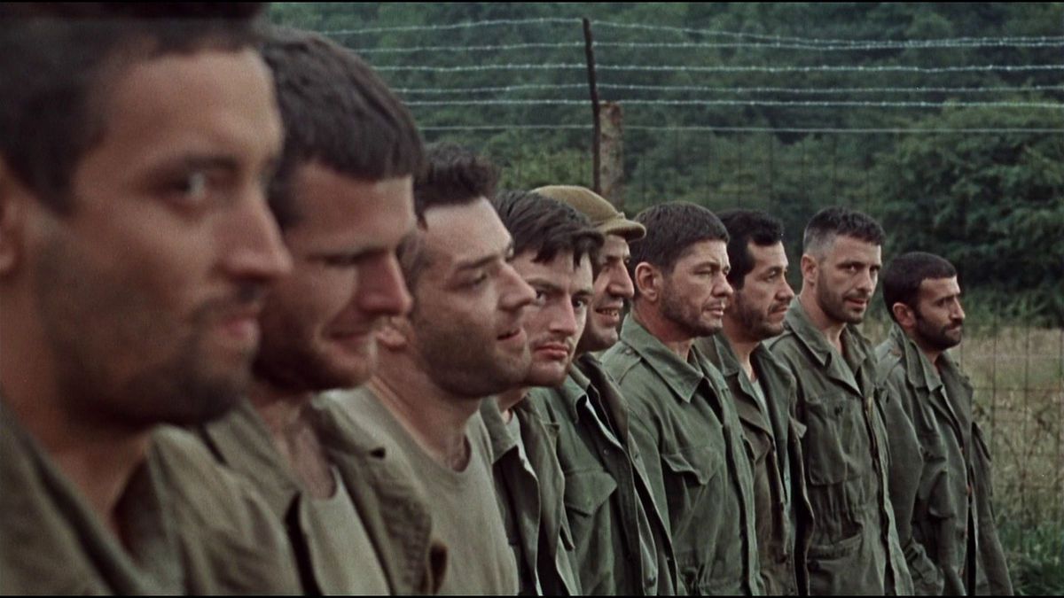 En närbild av flera soldater som står i kö bredvid ett taggtrådsstängsel i The Dirty Dozen.