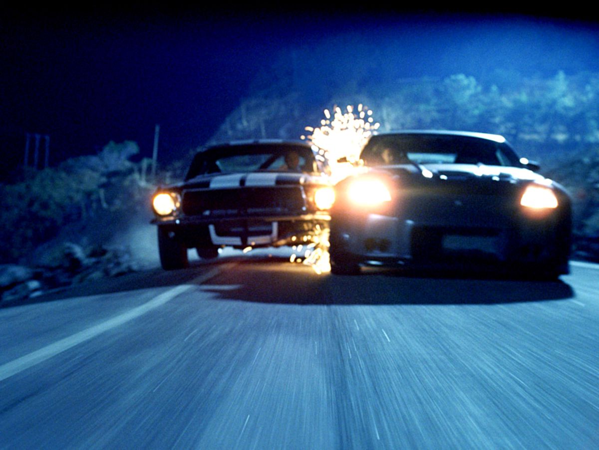 Gnistor flyger när två muskelbilar kolliderar medan de driver på en smal väg i The Fast and the Furious: Tokyo Drift.