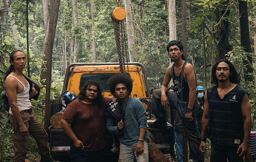 Fem personer som står bakom en lastbil med flak i djungeln.