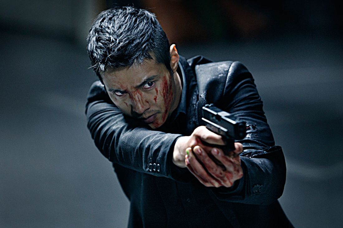 A man in a black suit (Won Bin) with blood on his face and hands trains the sights of a pistol at an off-screen target.