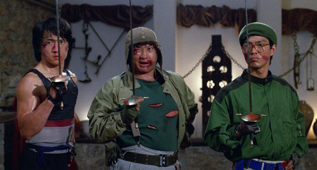 Jackie Chan, Sammo Hung, and Yuen Biao hold epees vertically in Wheels on Meals.