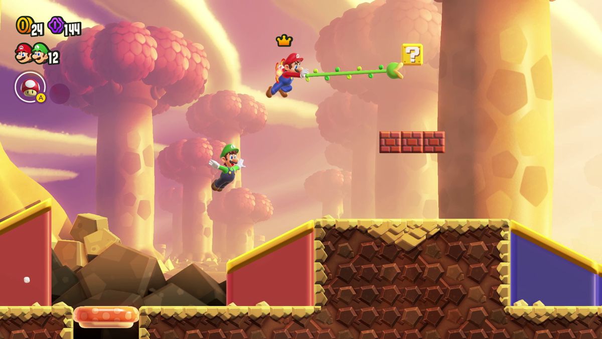Mario använder en gripkrok för att läsa ett frågeblock, med Luigi som hoppar bakom honom, i en skärmdump från Super Mario Bros. Wonder