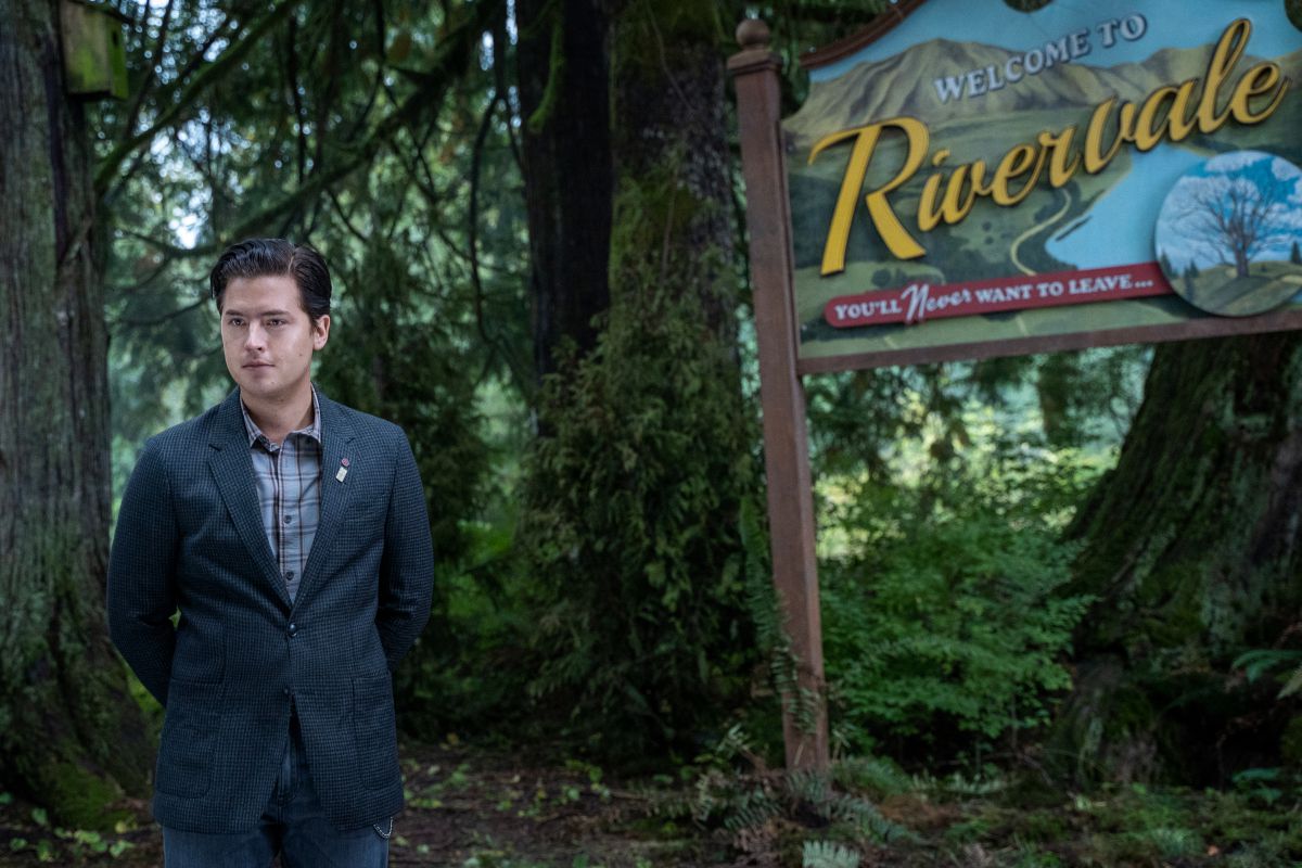 Jughead as a narrator standing in front of the “Rivervale” sign in the season 6 premiere of Riverdale.