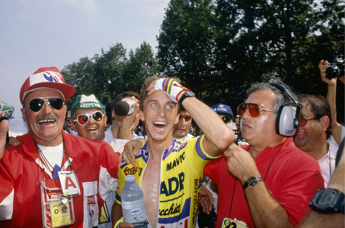 Greg LeMond håller sin hand mot ansiktet i misstro när han gratuleras efter en mirakulös seger i Tour de France.
