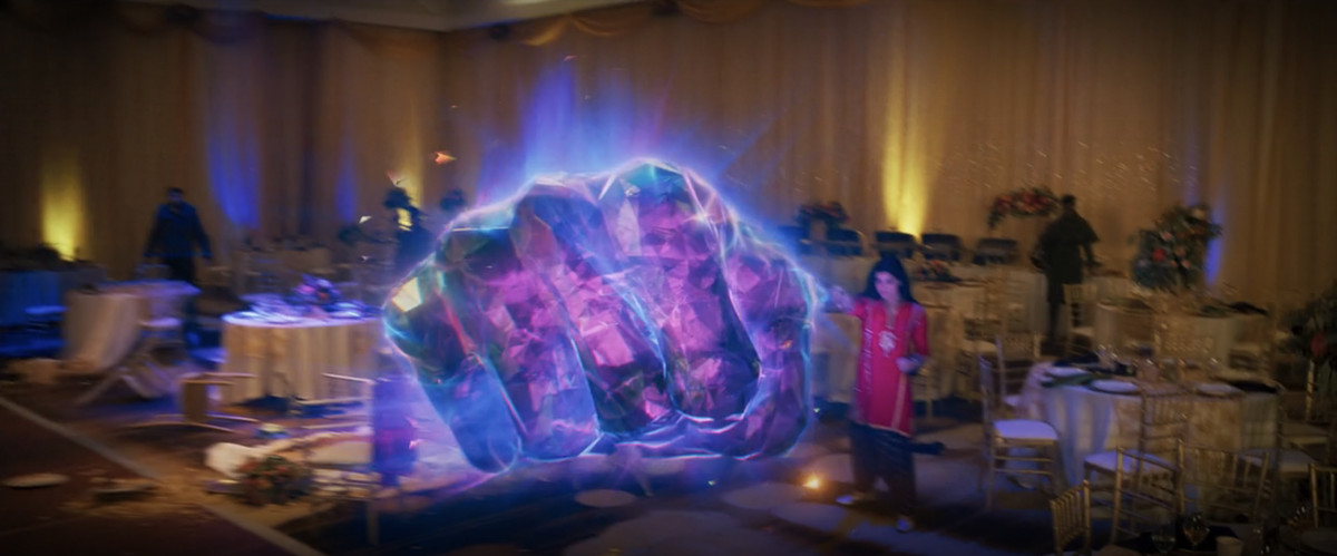 Kamala Khan/Ms.  Marvel kastar en stor stretchig punch gjord av facetterat hårt ljus i ett rum som är dekorerat för ett bröllop i Ms. Marvel. 