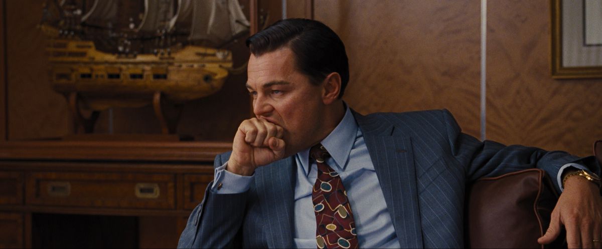 Leonardo DiCaprio bites his knuckle while wearing a suit in The Wolf of Wall Street.